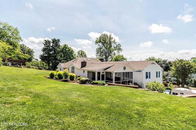 back of house with a sunroom and a lawn