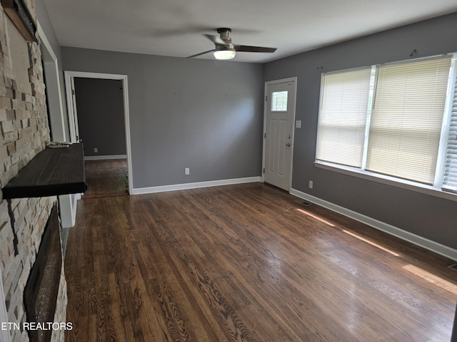 unfurnished living room featuring baseboards, visible vents, ceiling fan, and dark wood-style flooring