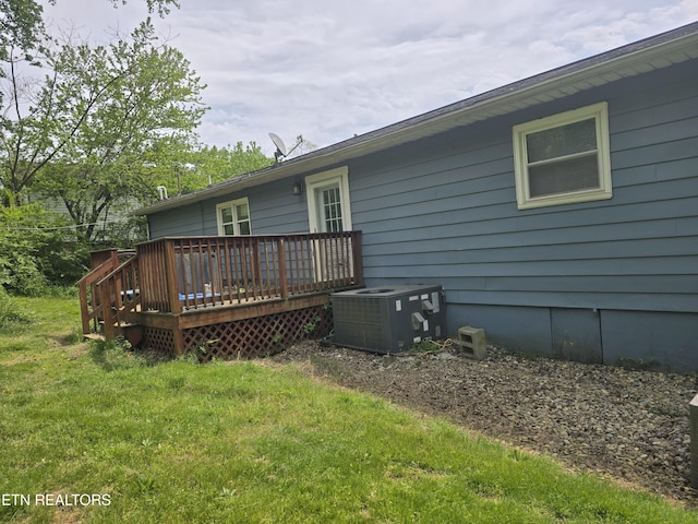 rear view of property featuring a wooden deck, a yard, and cooling unit