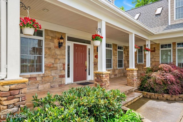 property entrance with covered porch, roof with shingles, and stone siding