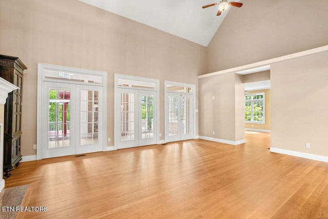 unfurnished living room with high vaulted ceiling, ceiling fan, light wood finished floors, and a fireplace