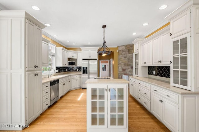 kitchen featuring tasteful backsplash, stainless steel appliances, crown molding, and a sink