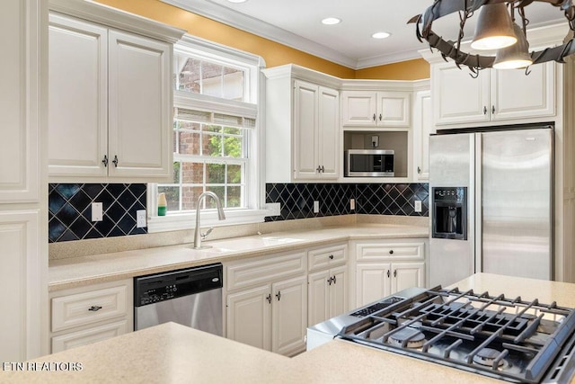 kitchen with ornamental molding, a sink, appliances with stainless steel finishes, and light countertops
