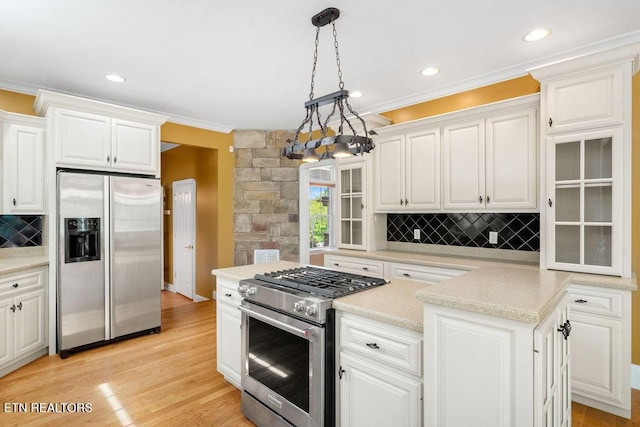 kitchen with stainless steel appliances, crown molding, backsplash, white cabinetry, and light countertops