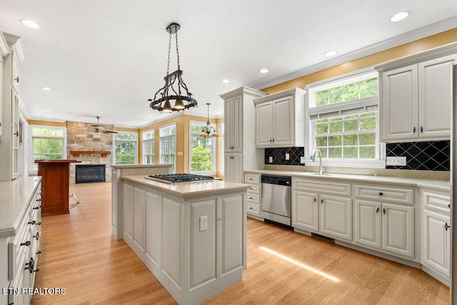 kitchen with appliances with stainless steel finishes, a kitchen island, light countertops, open floor plan, and a fireplace
