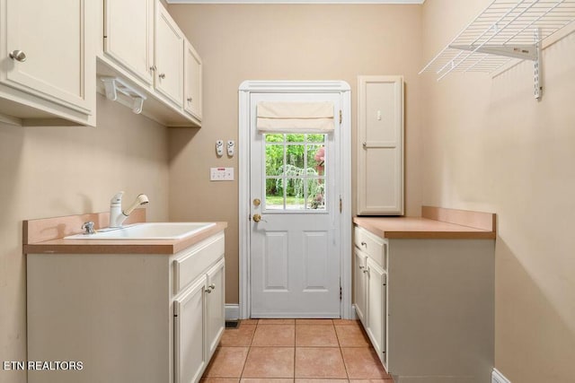 clothes washing area featuring light tile patterned floors and a sink