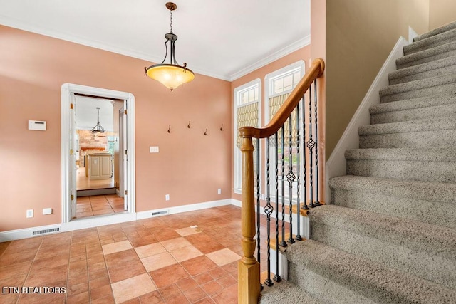 stairway with tile patterned floors, visible vents, crown molding, and baseboards