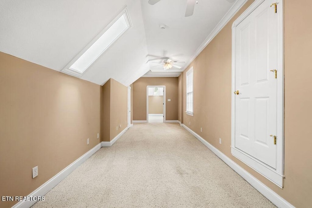 interior space featuring lofted ceiling with skylight, ceiling fan, and baseboards