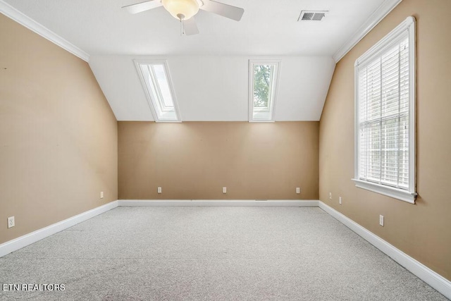 carpeted empty room featuring visible vents, a ceiling fan, vaulted ceiling, and baseboards