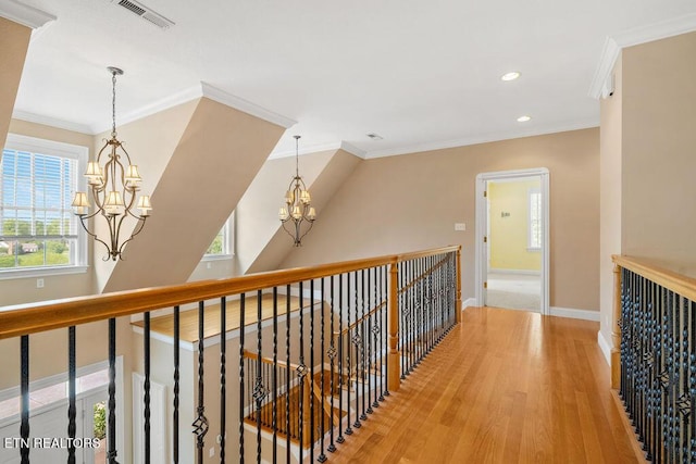 hallway with a chandelier, visible vents, a wealth of natural light, and an upstairs landing