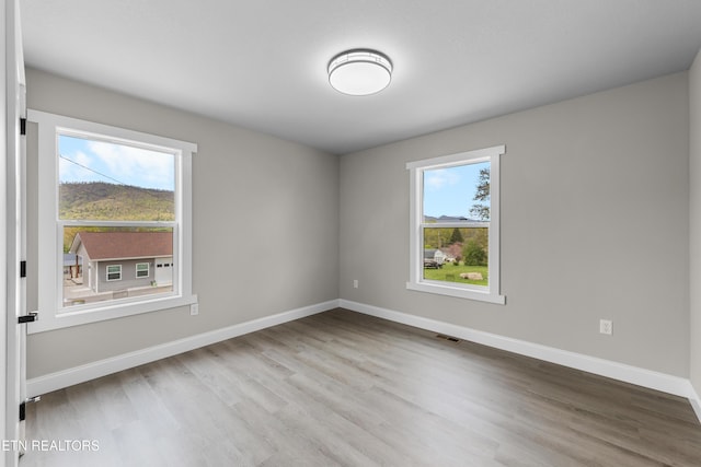 empty room with baseboards, wood finished floors, and visible vents