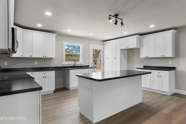 kitchen featuring dark countertops, a sink, recessed lighting, and white cabinetry