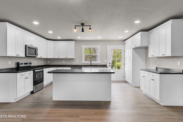 kitchen with dark countertops, appliances with stainless steel finishes, a sink, and recessed lighting