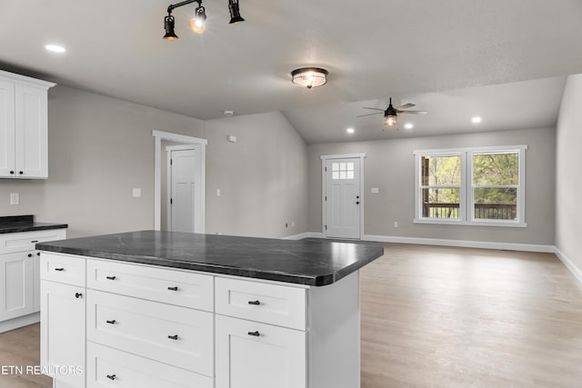kitchen with light wood finished floors, dark countertops, a ceiling fan, and baseboards