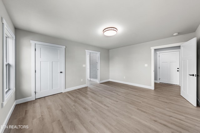 unfurnished bedroom with baseboards and light wood-style flooring