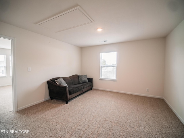 living area with attic access, light carpet, visible vents, and a healthy amount of sunlight