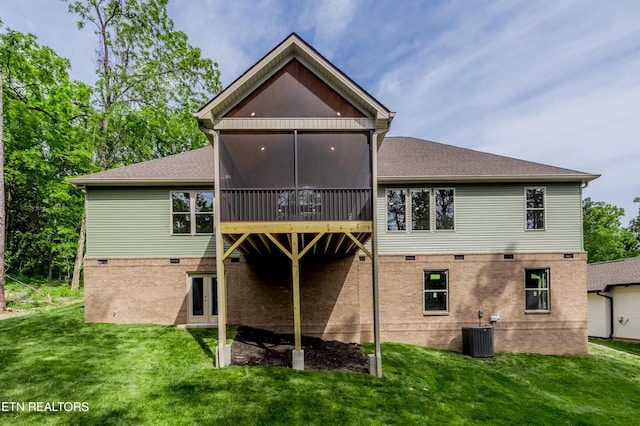 back of house featuring a lawn, a shingled roof, a sunroom, and central AC