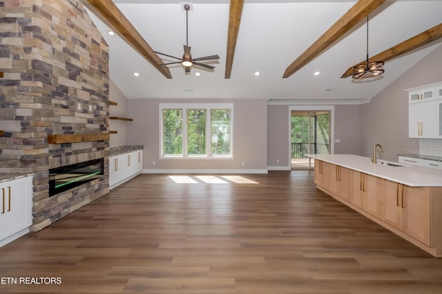kitchen featuring a fireplace, ceiling fan, open floor plan, and lofted ceiling with beams