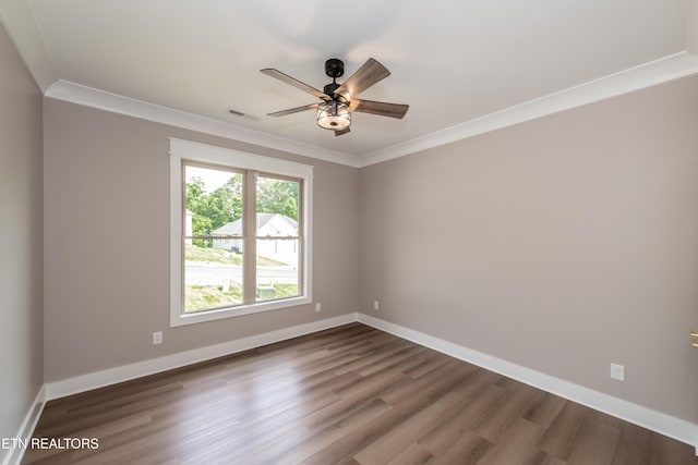unfurnished room with dark wood-style floors, visible vents, a ceiling fan, ornamental molding, and baseboards