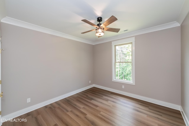 empty room with baseboards, wood finished floors, ceiling fan, and crown molding