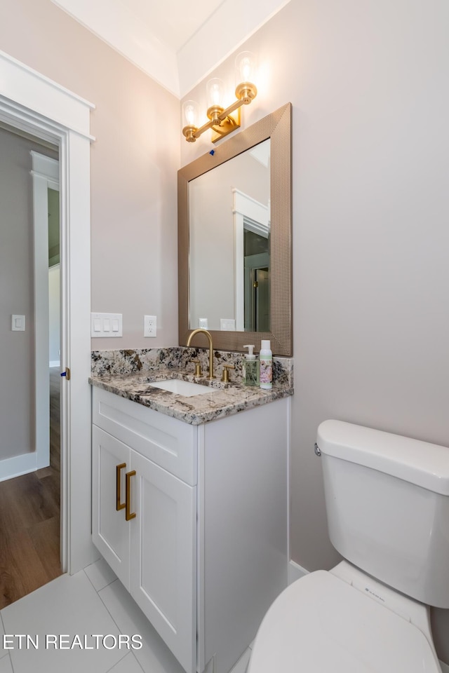 half bath with wood finished floors, vanity, a chandelier, and toilet