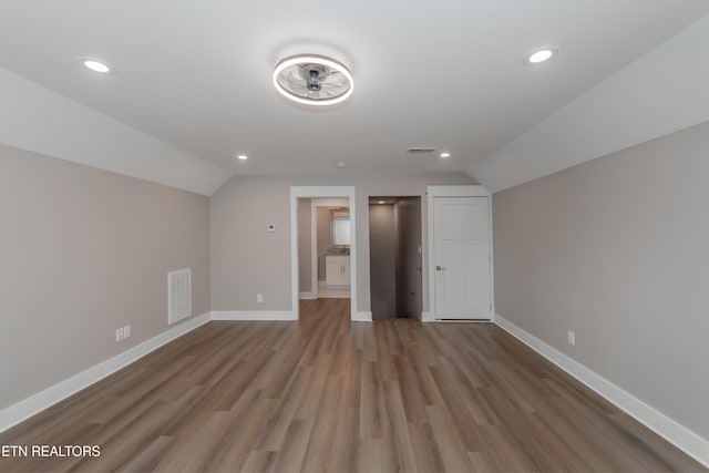 additional living space featuring vaulted ceiling, wood finished floors, baseboards, visible vents, and recessed lighting