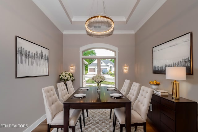 dining room with ornamental molding, wood finished floors, and a raised ceiling