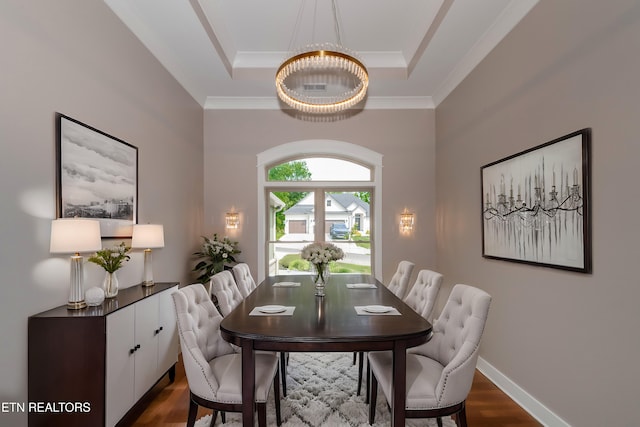 dining area featuring a tray ceiling, a notable chandelier, dark wood-style floors, and ornamental molding