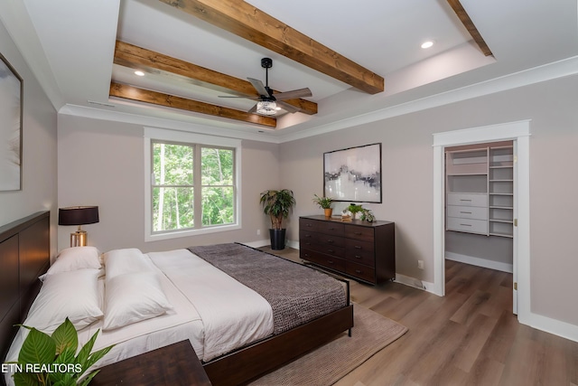 bedroom with recessed lighting, wood finished floors, a spacious closet, and beam ceiling