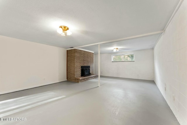unfurnished living room featuring a wood stove, a textured ceiling, and finished concrete flooring