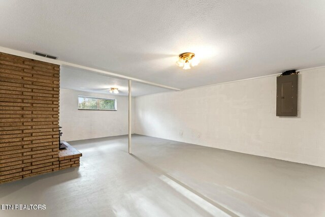 below grade area featuring a wood stove, a textured ceiling, electric panel, and visible vents