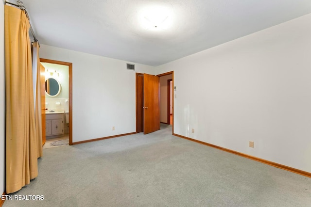 unfurnished bedroom with light colored carpet, baseboards, ensuite bathroom, and visible vents