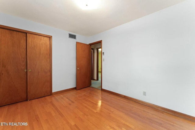 unfurnished bedroom featuring a closet, light wood-style flooring, visible vents, and baseboards