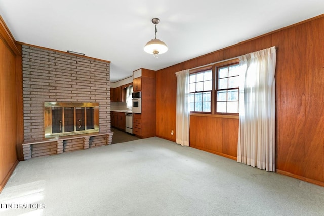 unfurnished living room featuring a brick fireplace, wood walls, and carpet floors
