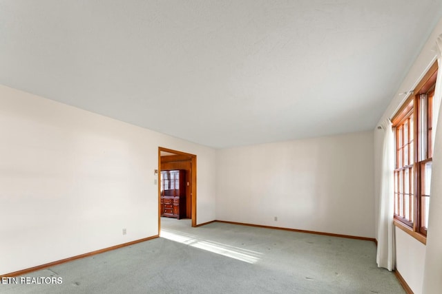 empty room featuring light carpet and baseboards