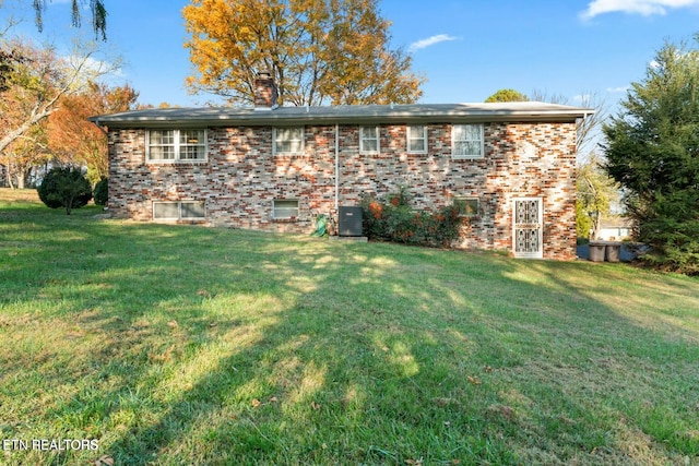 view of front of home with brick siding, a chimney, and a front lawn