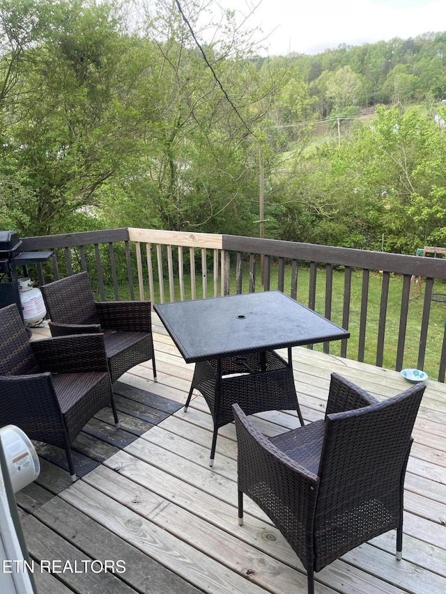 deck with outdoor dining space and a forest view