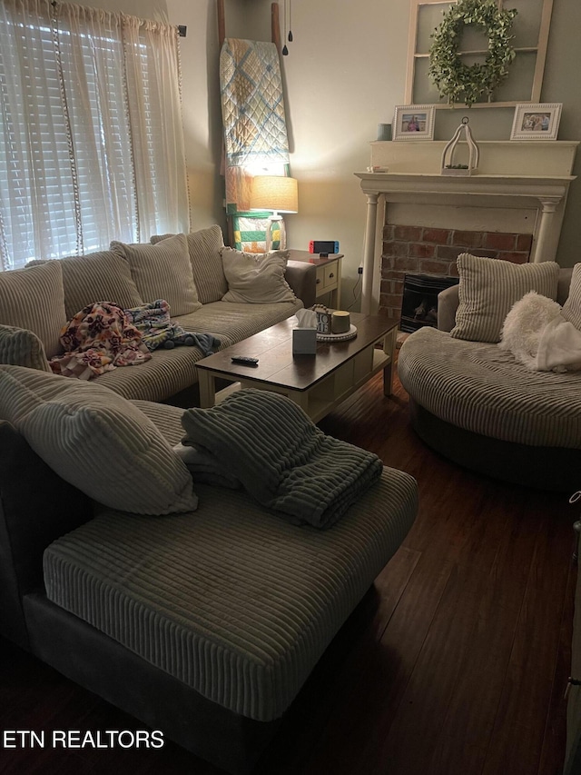 living room featuring a brick fireplace and wood finished floors