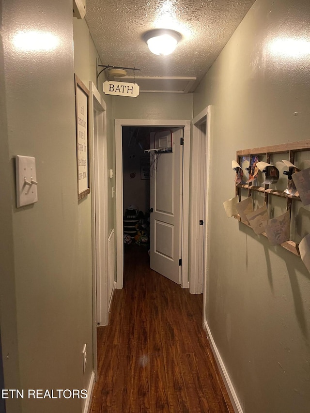 corridor with a textured ceiling and wood finished floors