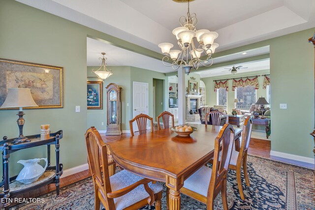 135 Austin Ln, Deer Lodge, TN 37726 - dining space featuring ceiling fan with notable chandelier, wood finished floors, baseboards, and a raised ceiling