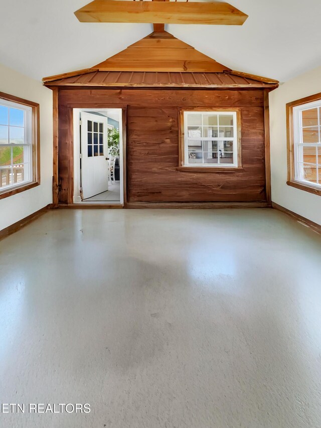 135 Austin Ln, Deer Lodge, TN 37726 - unfurnished living room featuring concrete flooring, baseboards, wood walls, and lofted ceiling
