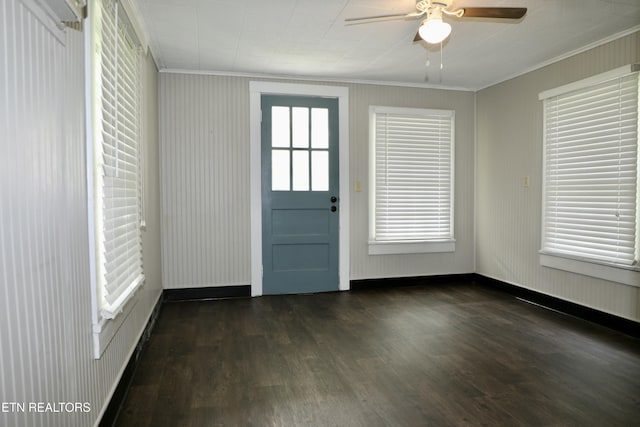 interior space with ornamental molding, ceiling fan, baseboards, and dark wood-type flooring