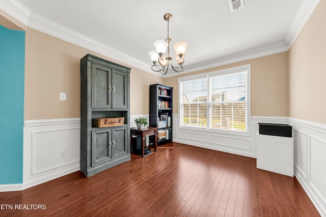 dining room featuring crown molding, a wainscoted wall, a notable chandelier, and visible vents