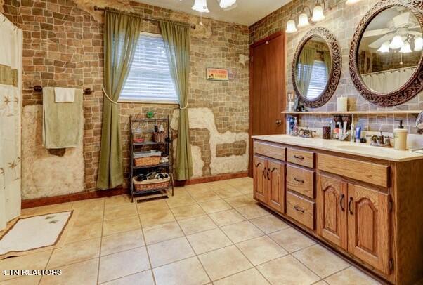 full bathroom with tile patterned flooring, baseboards, a sink, and double vanity