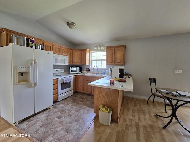 kitchen featuring light countertops, vaulted ceiling, a sink, white appliances, and a peninsula