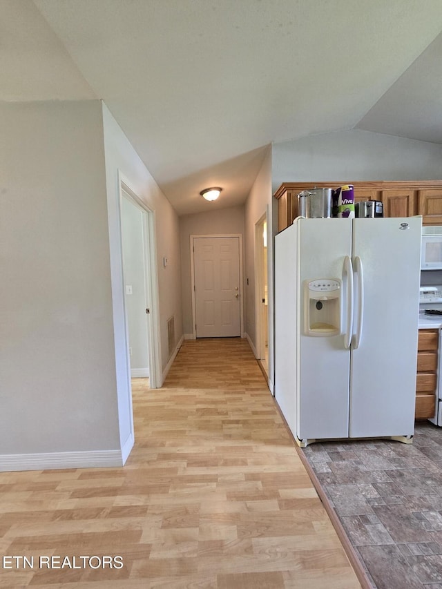 kitchen with visible vents, baseboards, light wood-style floors, lofted ceiling, and white appliances
