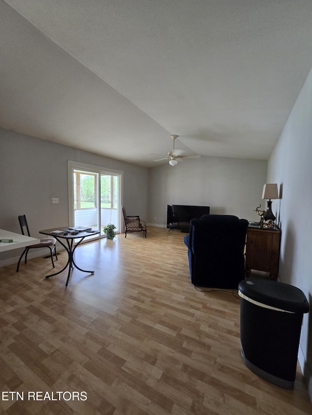 living area featuring light wood-style floors, vaulted ceiling, baseboards, and ceiling fan