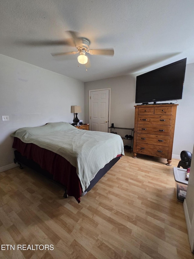 bedroom featuring baseboards, a ceiling fan, and light wood-style flooring
