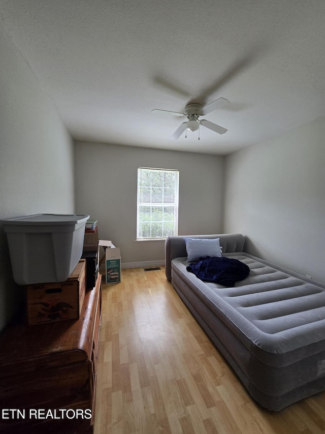 bedroom with light wood-style floors, visible vents, baseboards, and ceiling fan