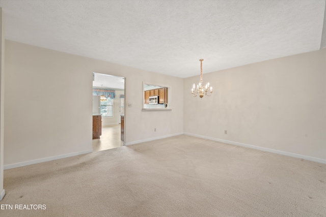 3804 Whitworth Dr, Knoxville, TN 37938 - spare room featuring baseboards, a textured ceiling, a chandelier, and light colored carpet